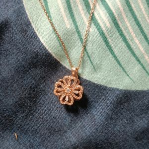 A gold coloured chain with flower locket.