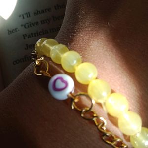 Yellow bracelet with attached 🫶 chain in middle