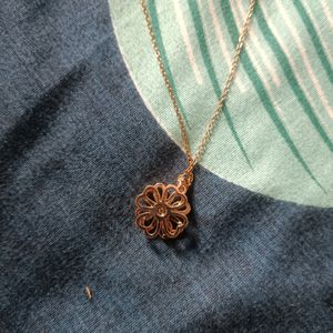 A gold coloured chain with flower locket.