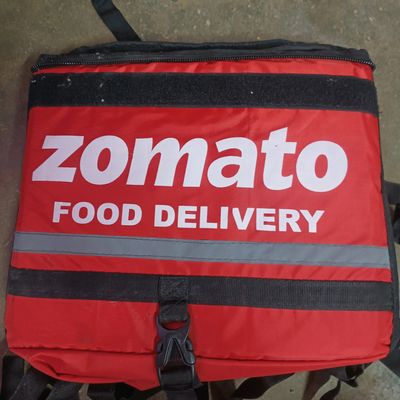 motorcycle rider with red zomato bag delivering food to a urban complex for  the fast growing food tech startup unicorn Stock Photo - Alamy