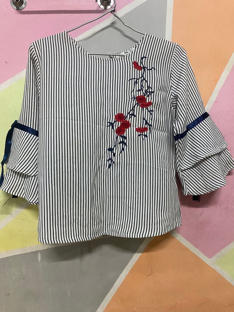 Thaoyu Fashion’s Beautiful Black Straight Line White Top With Full Sleeves And Little Flare To Bottom Of Sleeves With Ribbon Detail. Beautiful Red Flowers On It