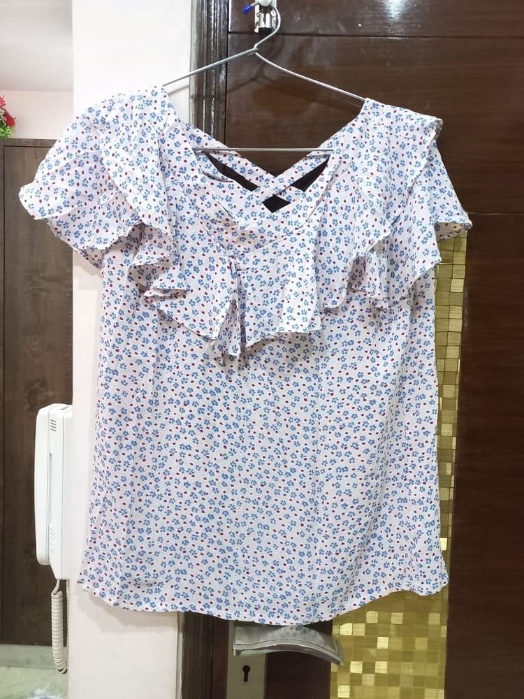 A pretty light pink and blue flower print top. It has a criss cross design on back. Size is medium but can fit a large too.